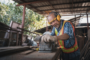 An elderly carpenter works the wood with meticulous care.