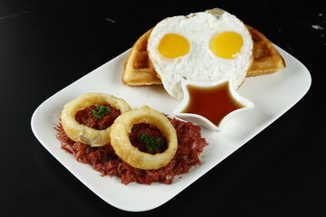 Corned beef hash breakfast with sunny side up eggs and waffles