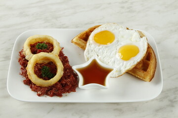 Corned beef hash breakfast with sunny side up eggs and waffles