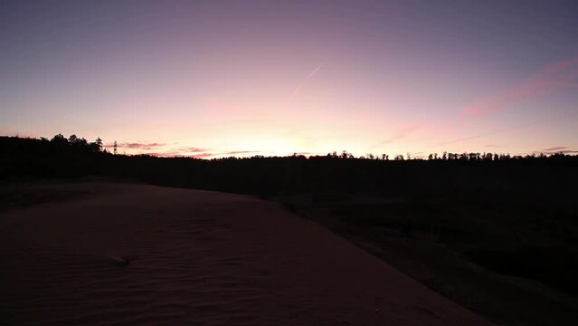 time lapse of a sunrise in purple light and a sand dune