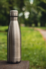 Water bottle. Reusable steel thermo water bottle on green grass. Sustainable lifestyle. Plastic...
