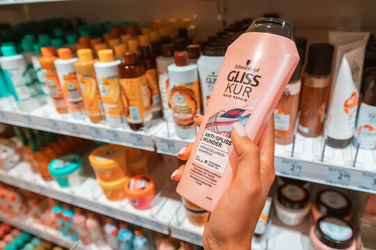 26 July 2022, Munster, Germany: Choosing Gliss Kur shampoo or bathing gel by Schwarzkopf in cosmetic store or supermarket, bottle in hand