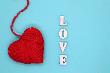 Valentine's Day concept. Wooden letters Love and heart of yarn on a blue background. Top view. Flat lay.