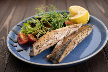 BBQ Grilled mackerel fish with lemon and tomatoes on plate. Menu restaurant