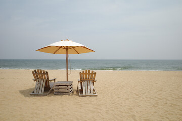 Beach Wooden chairs and a parasol on sand beach for looking sea view .vacation on the beach 