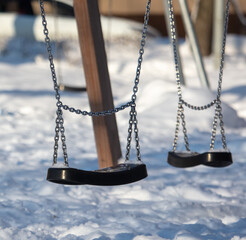 Children's swing in the snow in the park.