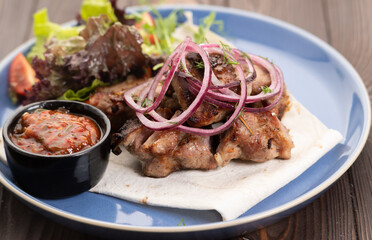 Healthy barbecue lean cubed pork kebabs served with a fresh lettuce, onion and tomato sauce, close up view