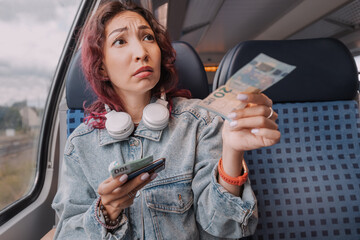 A sad girl pays a fine for a stowaway on a train or gives a bribe to a person on duty. The concept...