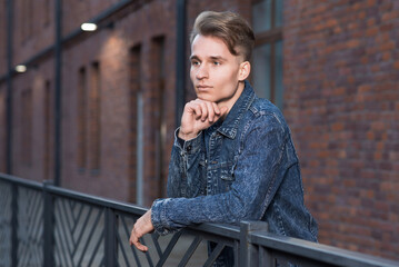 Fototapeta premium Portrait of a young Caucasian guy with a thoughtful look in a denim jacket.