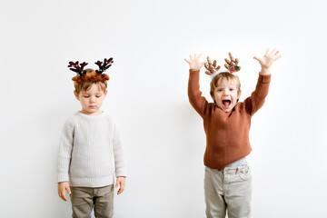 Little boys with Christmas headbands showing different emotions on light wall background