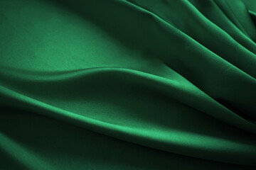 Dark emerald green silk satin. Soft folds. Fabric. Luxury background for design. Wavy lines....