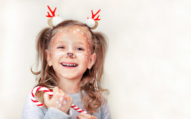a baby girl in Christmas horns holding a lollipop and laughing	