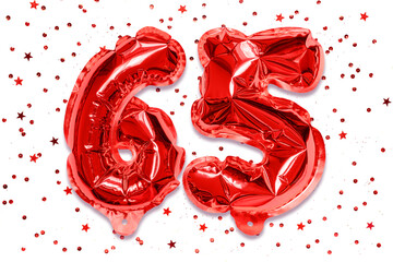 The number of the balloon made of red foil, the number sixty five on a white background with sequins. Birthday greeting card with inscription 65. Anniversary concept.