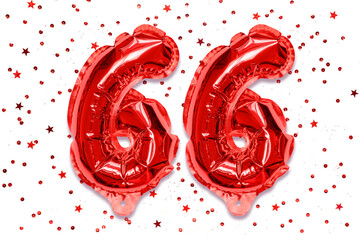 The number of the balloon made of red foil, the number sixty six on a white background with sequins. Birthday greeting card with inscription 66. Numerical digit. Celebration event.