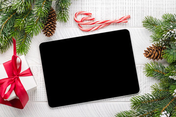 Tablet with blank screen, gift box and Christmas decor