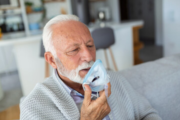 Sick elderly man making inhalation, medicine is the best medicine. Ill senior man wearing an oxygen mask and undergoing treatment for covid-19. Senior man with an inhaler