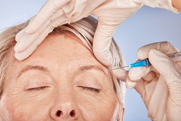 Face, hand and syringe for botox, cosmetic surgery and beauty against a grey studio back with...