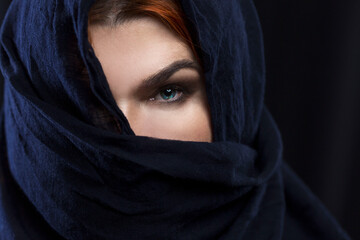 Naklejka premium An adult red-haired woman covered one eye with a handkerchief. Religion, traditions and culture. Close-up.
