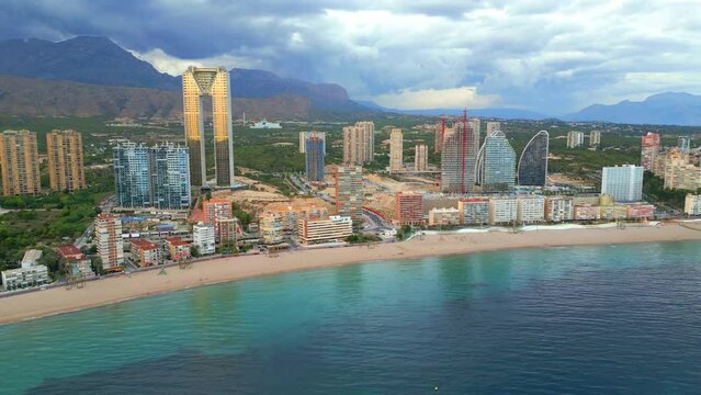 Aerial footage of Benidorm near Alicante, Spain. Objets in the video are the skyline with many skyscrapers like the Intempo building, a beach, and the sea. 4k drone footage.