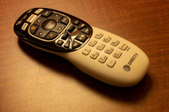 Oceanside, CA, USA - May 15, 2022: A DIRECTV remote control on a wooden table in a hotel room. DirecTV is an American multichannel video programming distributor.
