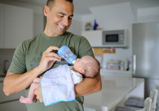 Happy father feeding newborn baby