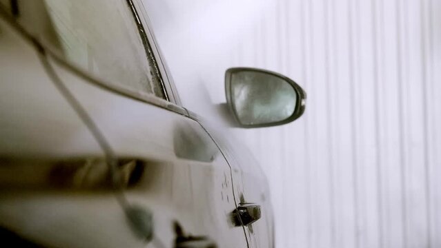 Car wash concept. Side view of a black car covered with water drops and beads on the door.