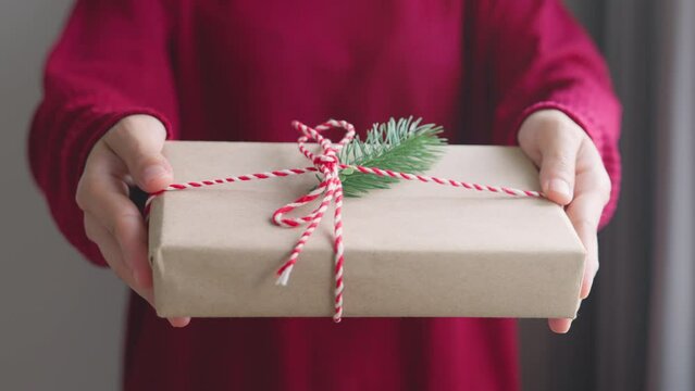 Presentation of a present for Christmas. Woman Hands holding craft paper gift box, for present Christmas and new year holiday.