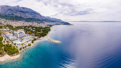Obraz premium Drone aerial view of Makarska city, Croatia. Sunset over the city, beach and se. Biokovo mountains in the background. Summer time.