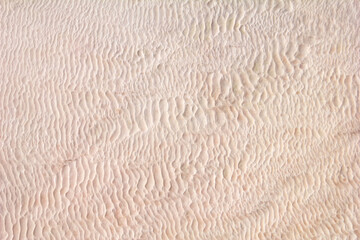 Beautiful nature pattern formed by calcium-rich mineral water. Intricate background - dried salt crust in white and light pink tones. The natural travertines of Pamukkale, central Turkey, Middle East