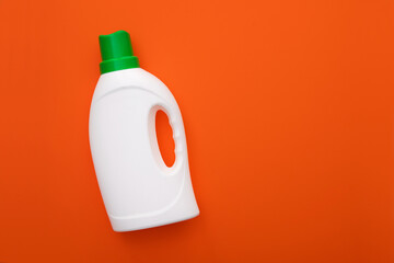 A bottle of detergent or soap on a bright orange color background.