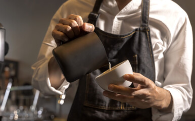 Close up Barista hands pouring white cream into cup making coffee latte art in coffeeshop, Coffee Barista