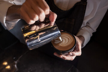 Coffee Barista pouring cream into cup making coffee latte art in coffee shop