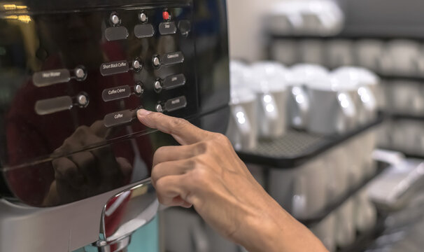 Close up finger pressing coffee machine in self service cafeteria, Coffee maker concept