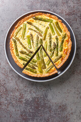 Asparagus Cheese Pie an easy and cheesy tart made with eggs, asparagus, and onions close-up in a plate on the table. Vertical top view from above