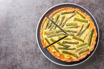 Homemade vegetarian creamy asparagus tart close-up in a plate on the table. Horizontal top view from above - Powered by Adobe