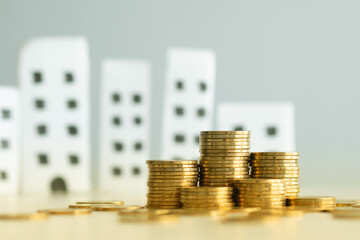 Stack of coin and apartment on background. Business and finance concept. Real estate, Property investment and asset management, Loan, Mortgage, Sale price and tax, Saving money for buy or rent home.