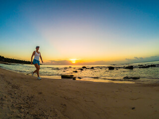 Fototapeta na wymiar Woman walking on sunny, tropical beach at daybreak 