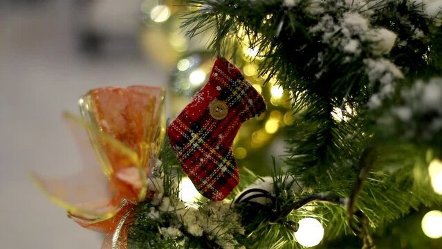 A New Year's plaid sock with a button hanging on a branch of a Christmas tree