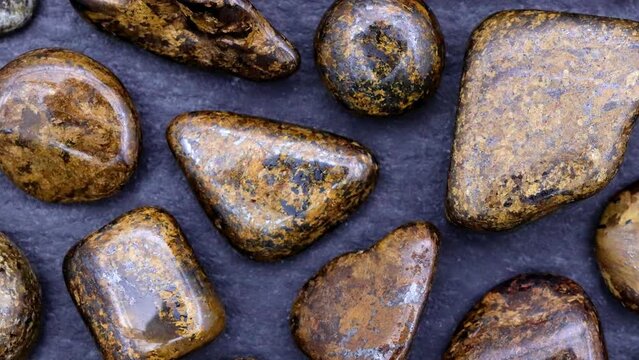 Bronzite rare jewel stones texture on black stone background. Moving right seamless loop backdrop.