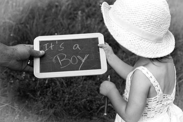 A young girl announces to the world the imminent birth of a baby brother.