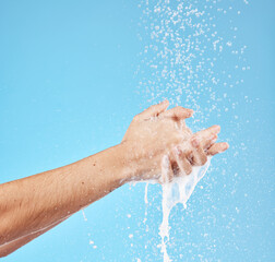 Fototapeta premium Cleaning hands, water splash and wash for hygiene, healthcare and wellness mockup on a blue studio background. Skin hydration, moisturizing skincare skin and protect from bacteria, germs and disease