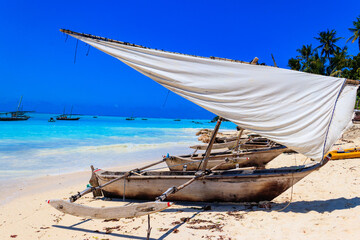 Traditional wooden dhow boats ashore on tropical sandy Nungwi beach in the Indian ocean on Zanzibar, Tanzania