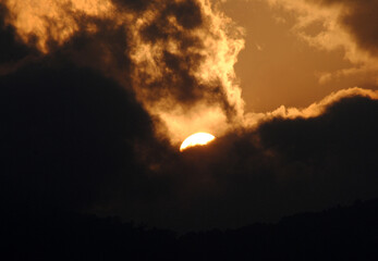 Fototapeta premium A magnificient view of sun hiding in the dark clouds during sunset looks mesmerizing as seen from Gangtok in Sikkim. Sunrise (dawn) and sunset (dusk) gives excellent view to capture in your camera.