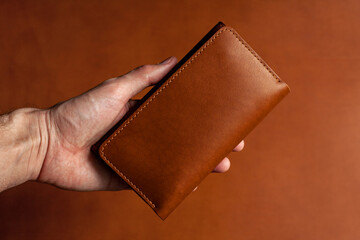 Leather wallet in hand on a brown background. For your logo.