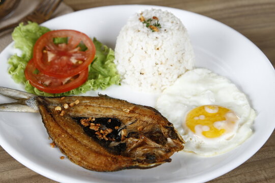 Filipino breakfast of fried bangus (milkfish) with garlic flakes and egg, lettuce, tomato and garlic fried rice