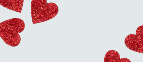 Red glittering hearts with place for text. Festive composition on a blue background.