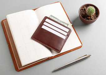 Leather cardholder with dollars and cards on the diary.