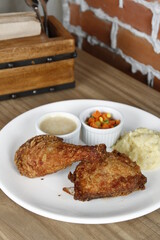 Crispy fried chicken with mash potatoes, corn and carrots, and gravy on a white plate