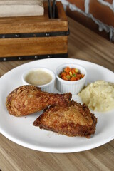 Crispy fried chicken with mash potatoes, corn and carrots, and gravy on a white plate