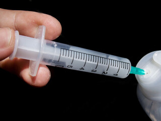 The syringe is taking the medicine on a black background. Close-up